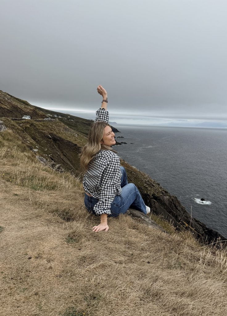Woman sitting at Slea Head Viewing point on the Dingle Peninsula in Ireland